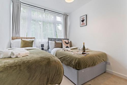 a bedroom with two beds next to a window at Cosy Home Next to Wembley Stadium in London