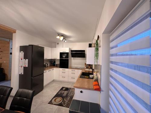 eine Küche mit weißen Schränken und einem schwarzen Kühlschrank in der Unterkunft Blue Lake Villa in Gostyczyn