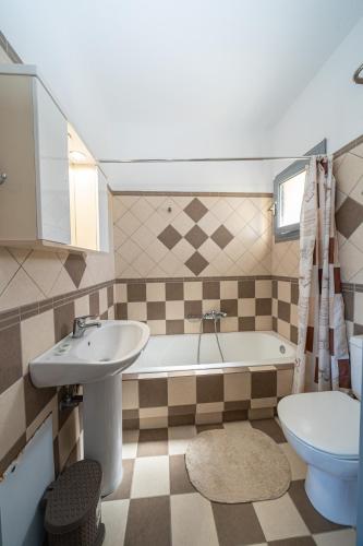 a bathroom with a sink and a tub and a toilet at Aridas at the Beach in Lourdata