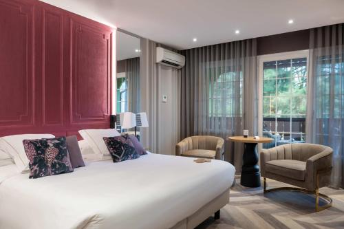 a bedroom with a large white bed and chairs at LA CHENEAUDIÈRE - Hôtel Spa - Relais & Châteaux - Restaurant étoilé in Colroy-la-Roche