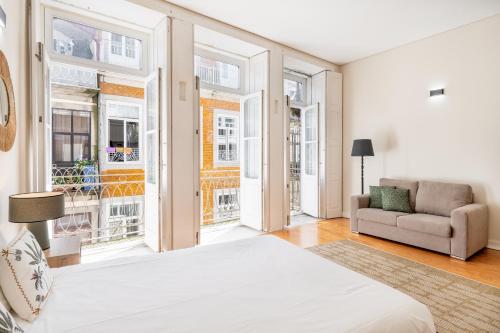 a bedroom with a bed and a couch and windows at VIVA Three Magi Residence in Porto