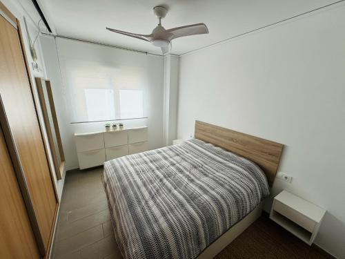 a small bedroom with a bed and a ceiling fan at Apartamento Playa Oliva in Oliva