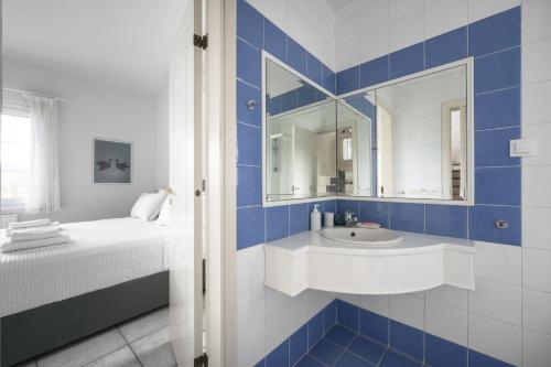 a blue and white bathroom with a sink and a bed at Paliouri Cottage by Luxlikehome in Paliouri