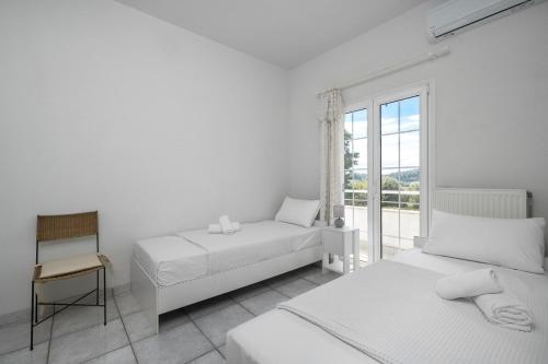 a white bedroom with two beds and a window at Paliouri Cottage by Luxlikehome in Paliouri