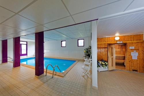 een groot zwembad in een groot gebouw bij Hôtel Club Le Risoux in Bois-dʼAmont