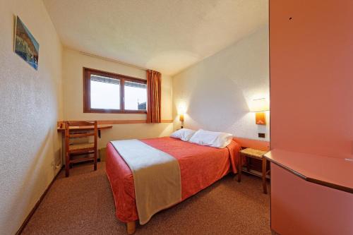 a hotel room with a bed and a desk at Hôtel Club Le Risoux in Bois-dʼAmont