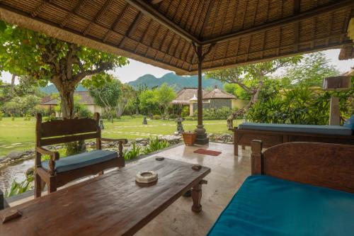 a room with a table and chairs and a view of a park at Taman Sari Bali Resort and Spa in Pemuteran