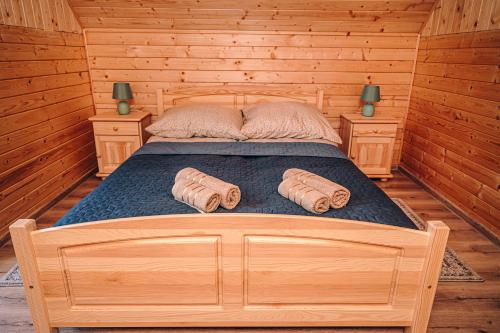 a bed in a log cabin with two pillows on it at Górskie Chatki Krysi i Piotrka Błękitny in Stronie Śląskie