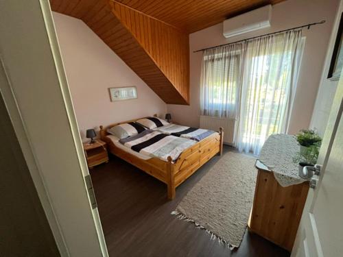 a bedroom with a bed and a large window at Bedi Apartmanház in Nagykanizsa