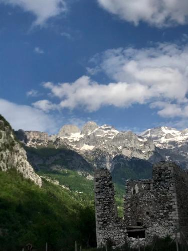 an old stone building with mountains in the background at Bujtina Pllumi Theth in Theth