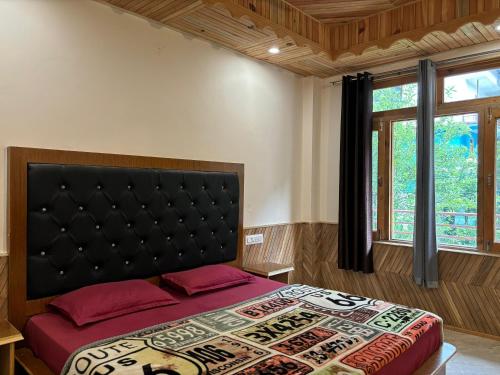 a bedroom with a bed with a black headboard and a window at Pine view kasol in Kasol