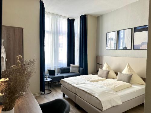 een slaapkamer met een bed, een stoel en een raam bij City Hotel Hameln in Hameln
