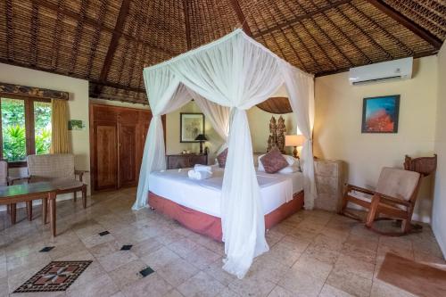 a bedroom with a bed with a canopy at Taman Sari Bali Resort and Spa in Pemuteran
