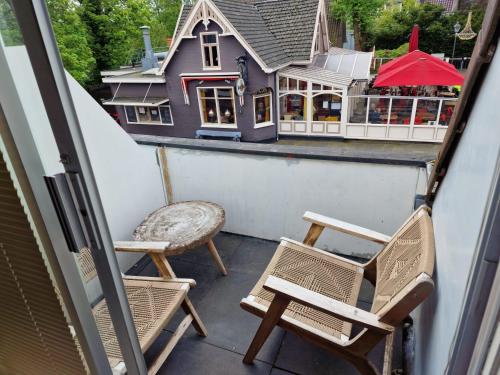 a balcony with chairs and a house in the background at Hotel Liberte in Schoorl