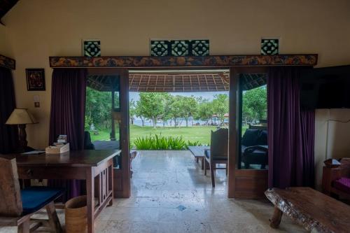 a living room with a door open to a yard at Taman Sari Bali Resort and Spa in Pemuteran