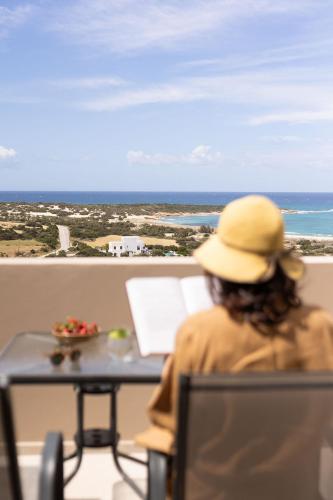 a woman sitting at a table looking out at the ocean at Olive Vista Suites in Kastraki