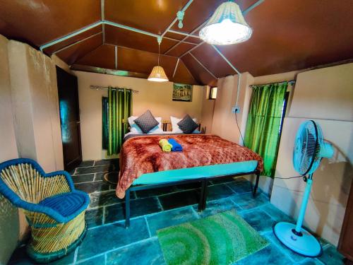 a bedroom with a bed and a fan and a chair at Raadballi Retreat in Kangra