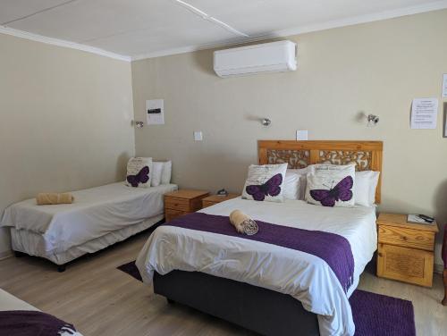 a bedroom with two beds with purple butterflies on them at Palms Lodge in Kroonstad