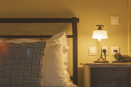 a bedroom with a bed with a lamp and a phone at Arethousa Hotel in Katakolon