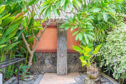 a garden with palm trees and a building at Taman Sari Bali Resort and Spa in Pemuteran