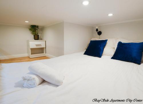 1 dormitorio con 1 cama blanca grande con almohadas azules en BaySide Apartments Center City, en Gdansk