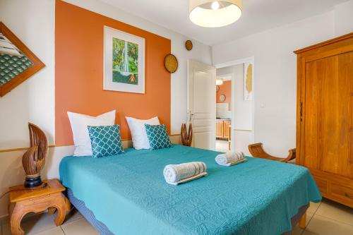 a bedroom with a blue bed with orange walls at Terre des îles - Grande Anse - lodges avec piscines privées in Petite Île