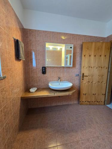 La salle de bains est pourvue d'un lavabo et d'une porte en bois. dans l'établissement Antico Fienile Agritur, à Mezzocorona