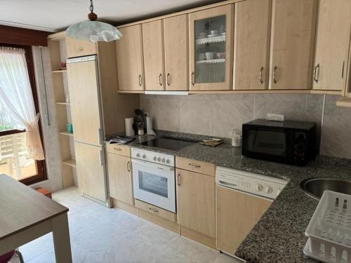 a kitchen with wooden cabinets and a microwave at Unquera (mar y montaña) in Unquera