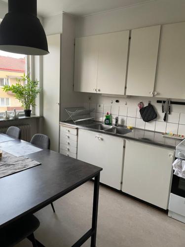 cocina con armarios blancos y mesa negra en Mysiga Lägenheten I Örebro, en Örebro