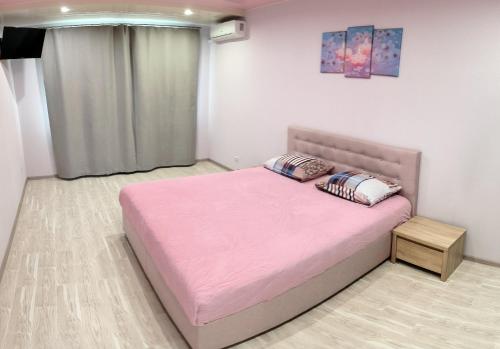 a bedroom with a pink bed with two pillows on it at Apartment near metro Pozniaky in Kyiv