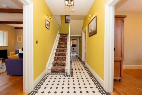 a staircase in a home with yellow walls and a checkered floor at Historic Luxury House in Corrofin