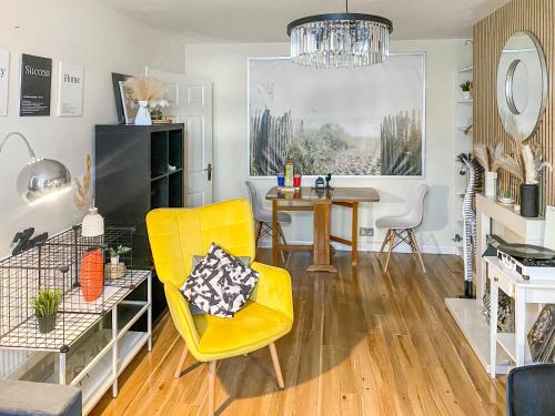 ein Wohnzimmer mit einem gelben Stuhl und einem Tisch in der Unterkunft 3Bed 2Bath with Garden sauna & Hot Tub in London