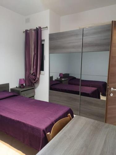 1 Schlafzimmer mit 2 Betten mit lila Bettwäsche und einem Spiegel in der Unterkunft 3 bedrooms flat at Attard in Attard