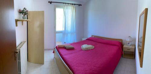 um quarto com uma cama vermelha e um cobertor rosa em Casa ichnusa 8 em Santa Teresa Gallura