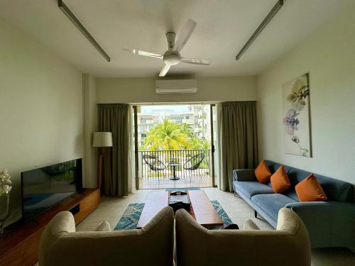 a living room with a blue couch and a tv at By the Sea- Pool and Sea View in Batu Ferringhi
