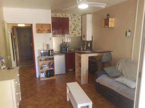 un petit salon avec un canapé et une cuisine dans l'établissement Studio place Saint clair, au Cap d'Agde