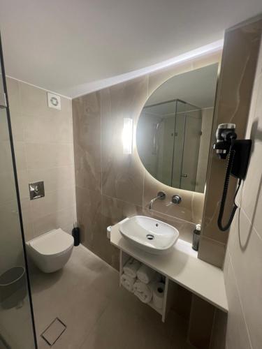 uma casa de banho com um lavatório, um WC e um espelho. em Aktaion City Hotel em Gythio