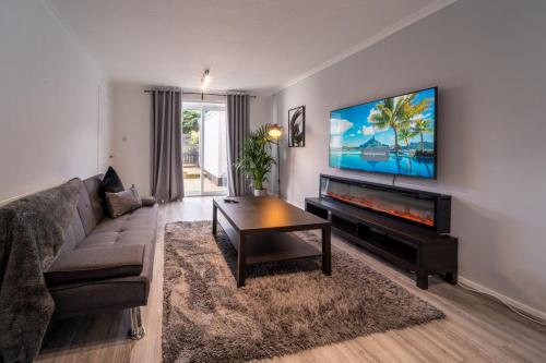 a living room with a couch and a flat screen tv at Spacious 3 Bed House, 5mins to HS2/ NEC/Airport. in Marston Green