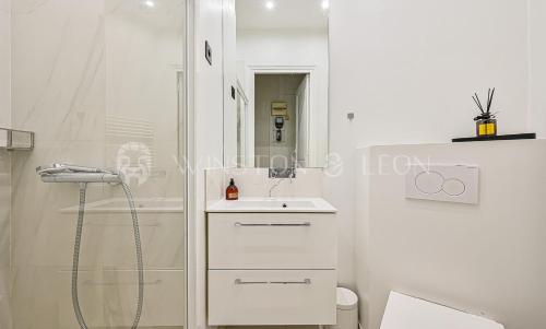 une salle de bain blanche avec une douche et un lavabo dans l'établissement Appartement Paris 7ème Invalides/ Tour Eiffel 1er étage, à Paris