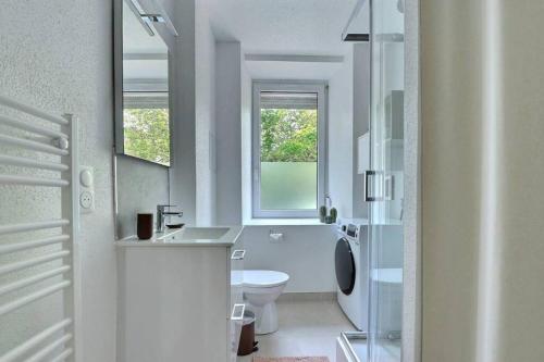 une salle de bain blanche avec toilettes et fenêtre dans l'établissement Le Coquelicot- Coquet, à Mulhouse