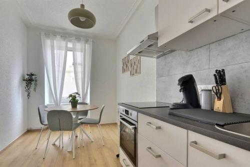 une cuisine avec une table et un comptoir dans l'établissement Le Coquelicot- Coquet, à Mulhouse