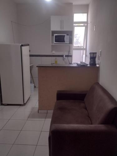 a living room with a couch and a kitchen at Fique tranquilo, bem localizado! in Araxá