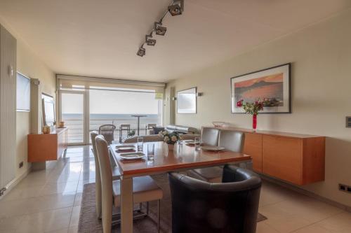"Romantica" - Luxery Apartment with Seaview في أوستند: مطبخ وغرفة طعام مع طاولة وكراسي
