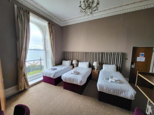 a hotel room with two beds and a window at Cliffe Norton in Tenby
