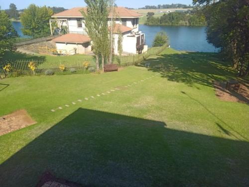 a large yard with a house and a lake at Emufuleni river logde in Vanderbijlpark