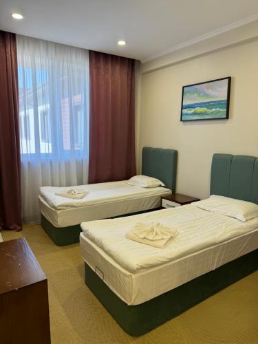 a hotel room with three beds and a window at SULO Atyrau Hotel in Atyraū