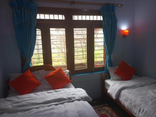 dwa łóżka w pokoju z dwoma oknami w obiekcie Galaxy Inn Guest House w mieście Pokhara