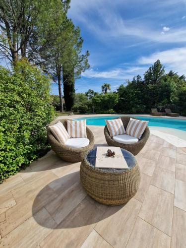 d'une terrasse avec des chaises en osier et une table à côté de la piscine. dans l'établissement L' Esmerand, à Cotignac