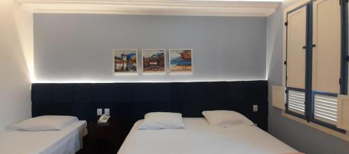 duas camas individuais num quarto com duas fotografias na parede em Hotel Pousada Minas Gerais em Ouro Preto