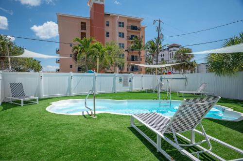 um quintal com uma piscina com duas cadeiras e um baloiço em C7-Dolphin em St. Pete Beach